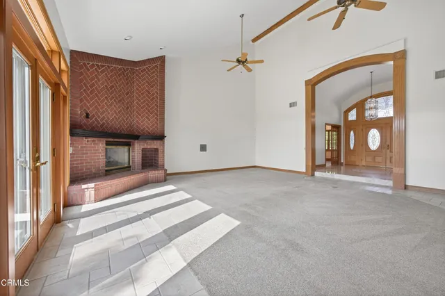 an empty room with windows and chandelier fan