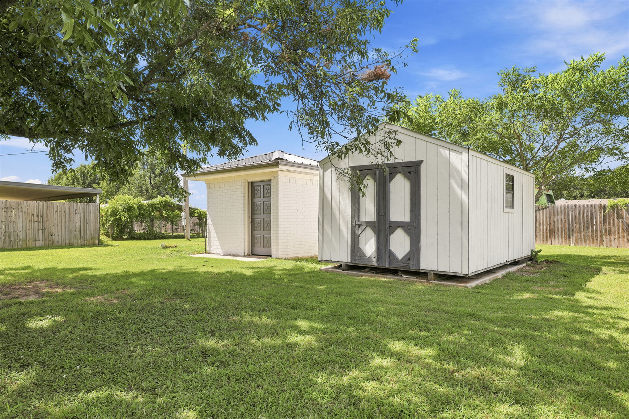 633 Swinney Road Mead, OK 73449 - Photo 23 of 32 Expansive backyard featuring a manicured lawn, a detached storage shed with double doors, and a separate brick structure with a metal roof