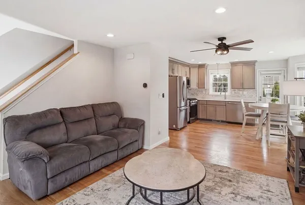 a living room with furniture kitchen view and a wooden floor