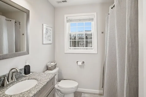 a bathroom with a granite countertop sink toilet a mirror and shower