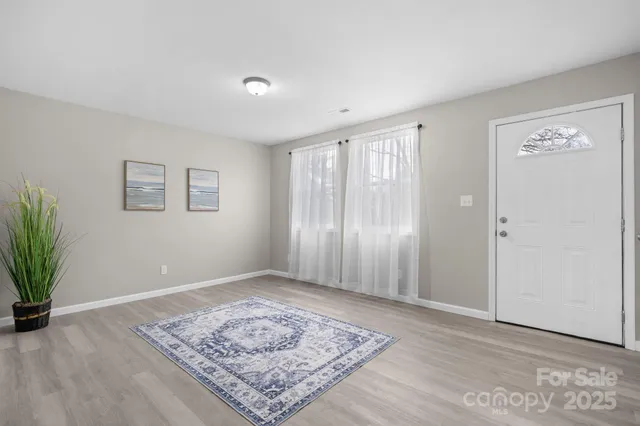 a view of an empty room with window and wooden floor
