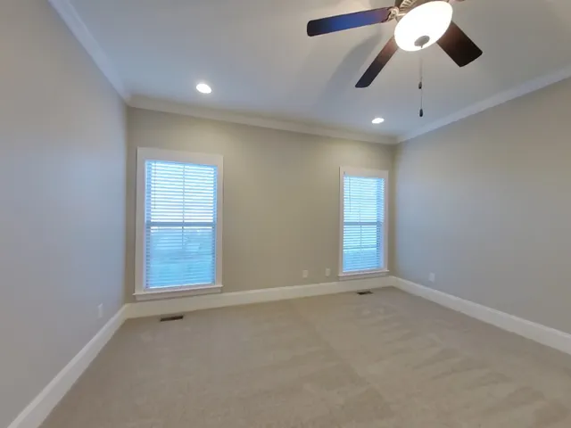 an empty room with a ceiling fan and windows