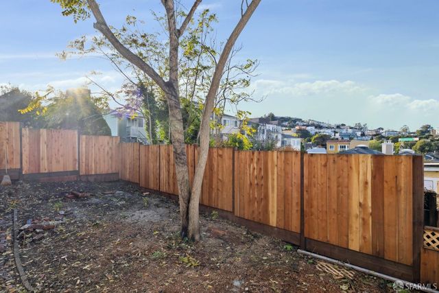 a view of a backyard with wooden fence and a large tree