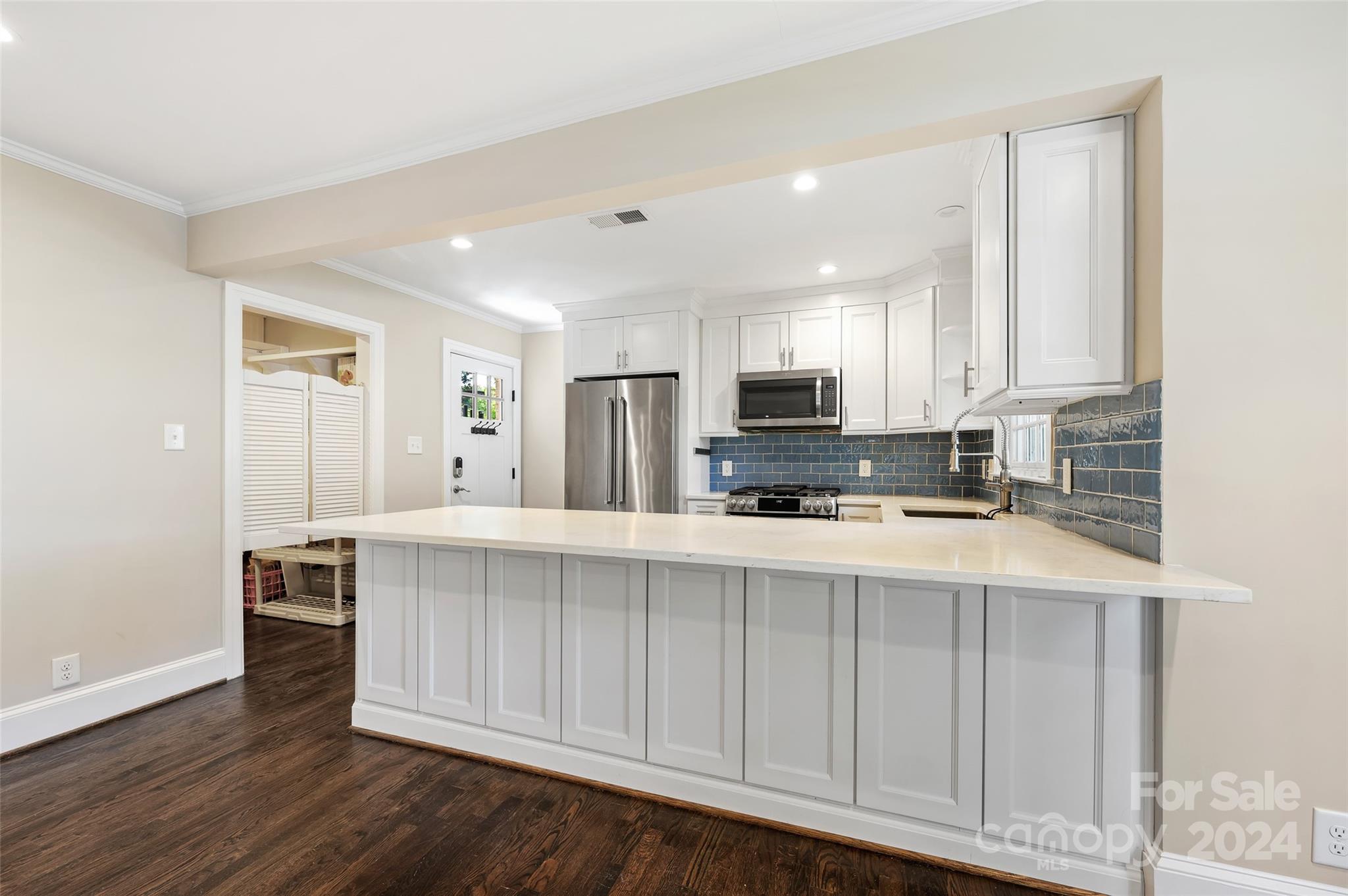 3233 Pinehurst Place Charlotte, NC 28209 - Photo 12 of 39 a large white kitchen with stainless steel appliances granite countertop a stove a sink a refrigerator white cabinets and wooden floor