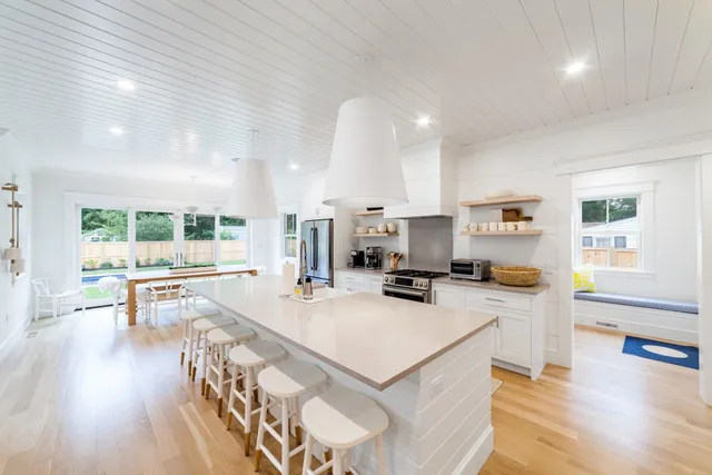 a kitchen with a stove a refrigerator a sink a dining table and chairs with wooden floor