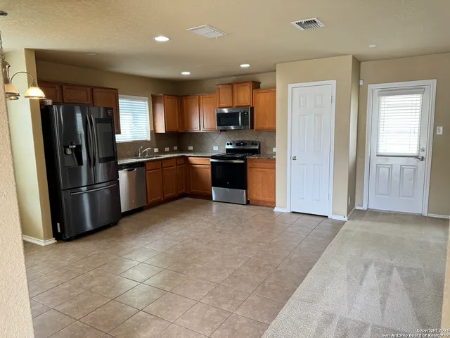 a large kitchen with stainless steel appliances granite countertop a refrigerator and a stove top oven