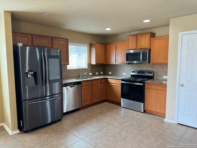 a kitchen with granite countertop a refrigerator stove and microwave