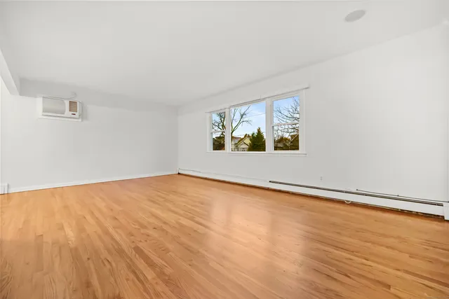 an empty room with wooden floor and window