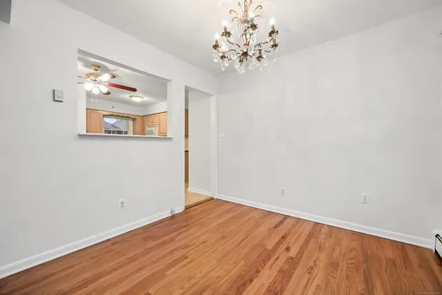 an empty room with wooden floor chandelier and window
