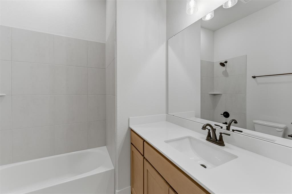 2204 Continent Court Krum, TX 76249 - Photo 19 of 28 Bathroom vanity featuring an integrated sink, broad countertop, and wood-finish cabinetry