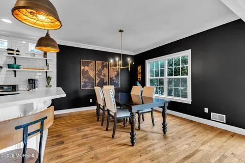 a kitchen with stainless steel appliances kitchen island granite countertop a table chairs in it and wooden floors