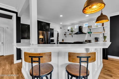 a kitchen with stainless steel appliances granite countertop a stove a refrigerator a sink a dining table and chairs with wooden floor
