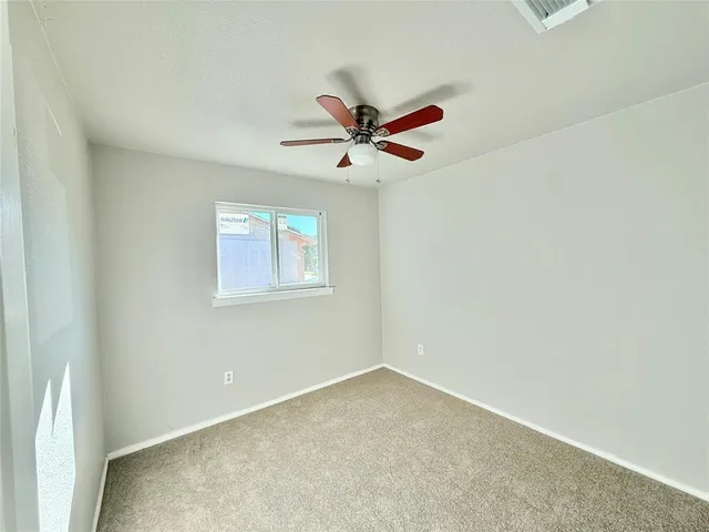 an empty room with a window and a fan