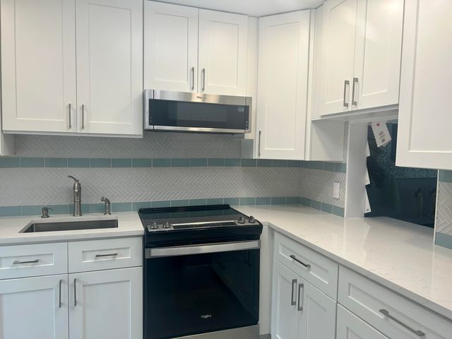 a kitchen with stainless steel appliances granite countertop a refrigerator a sink and white cabinets