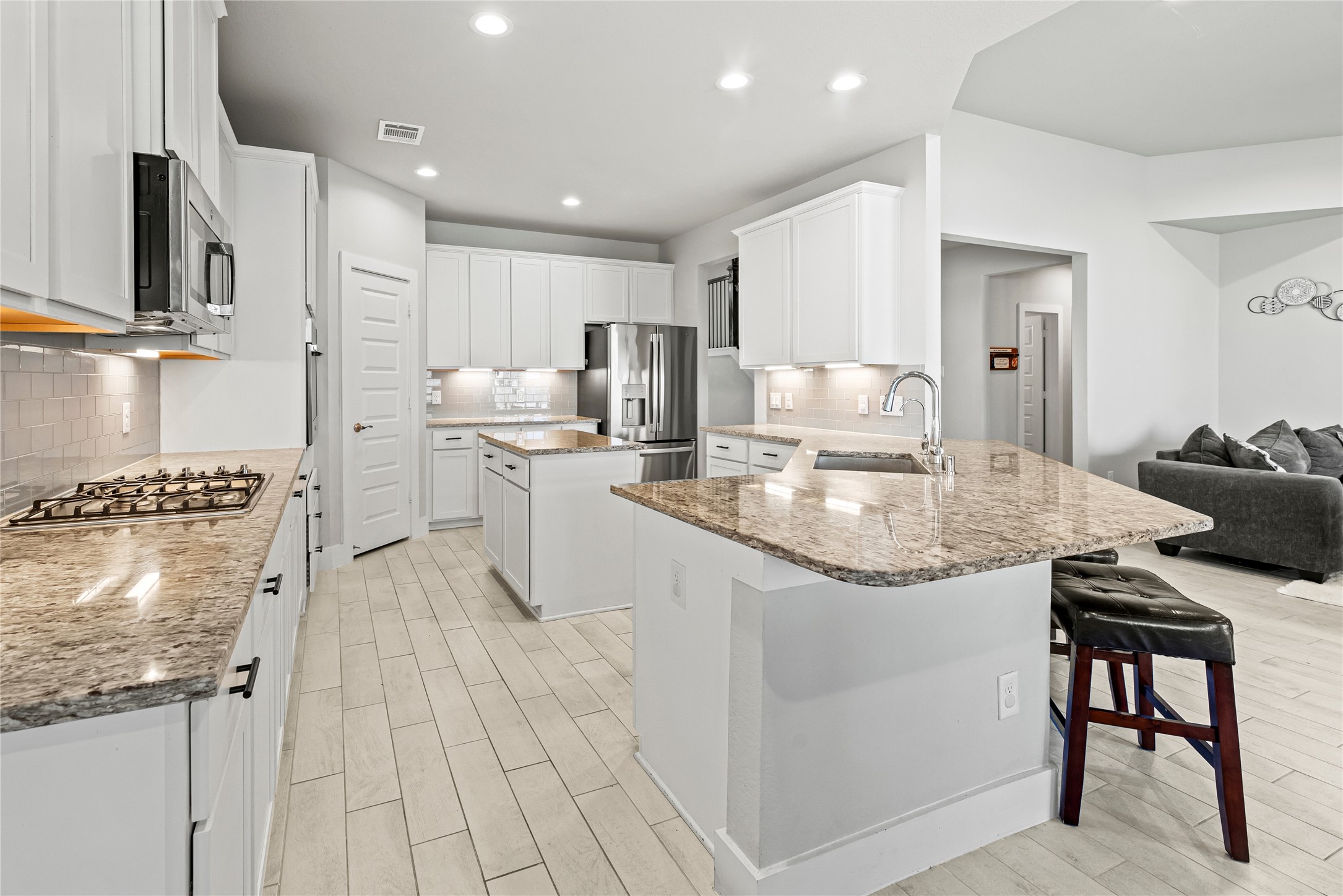 1600 Del Sol Rdg Lane Katy, TX 77493 - Photo 6 of 28 Step into this beautiful kitchen featuring rich white cabinetry with under-cabinet lighting, stainless steel appliances, and breakfast bar seating, all seamlessly opening to the family room for effortless everyday living and entertaining.