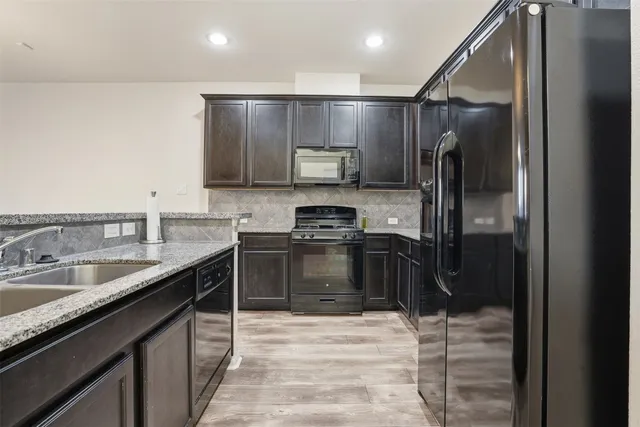 a kitchen with stainless steel appliances granite countertop a sink stove and refrigerator