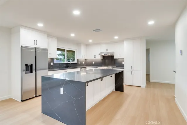 a kitchen with stainless steel appliances granite countertop a sink a refrigerator and a stove