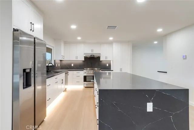 a large kitchen with stainless steel appliances kitchen island a stove a refrigerator a sink a counter top and grass