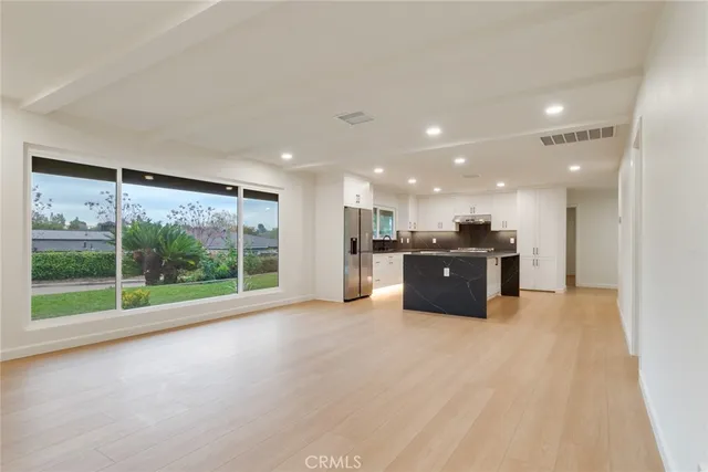 a large room with stainless steel appliances wooden floor and a large window