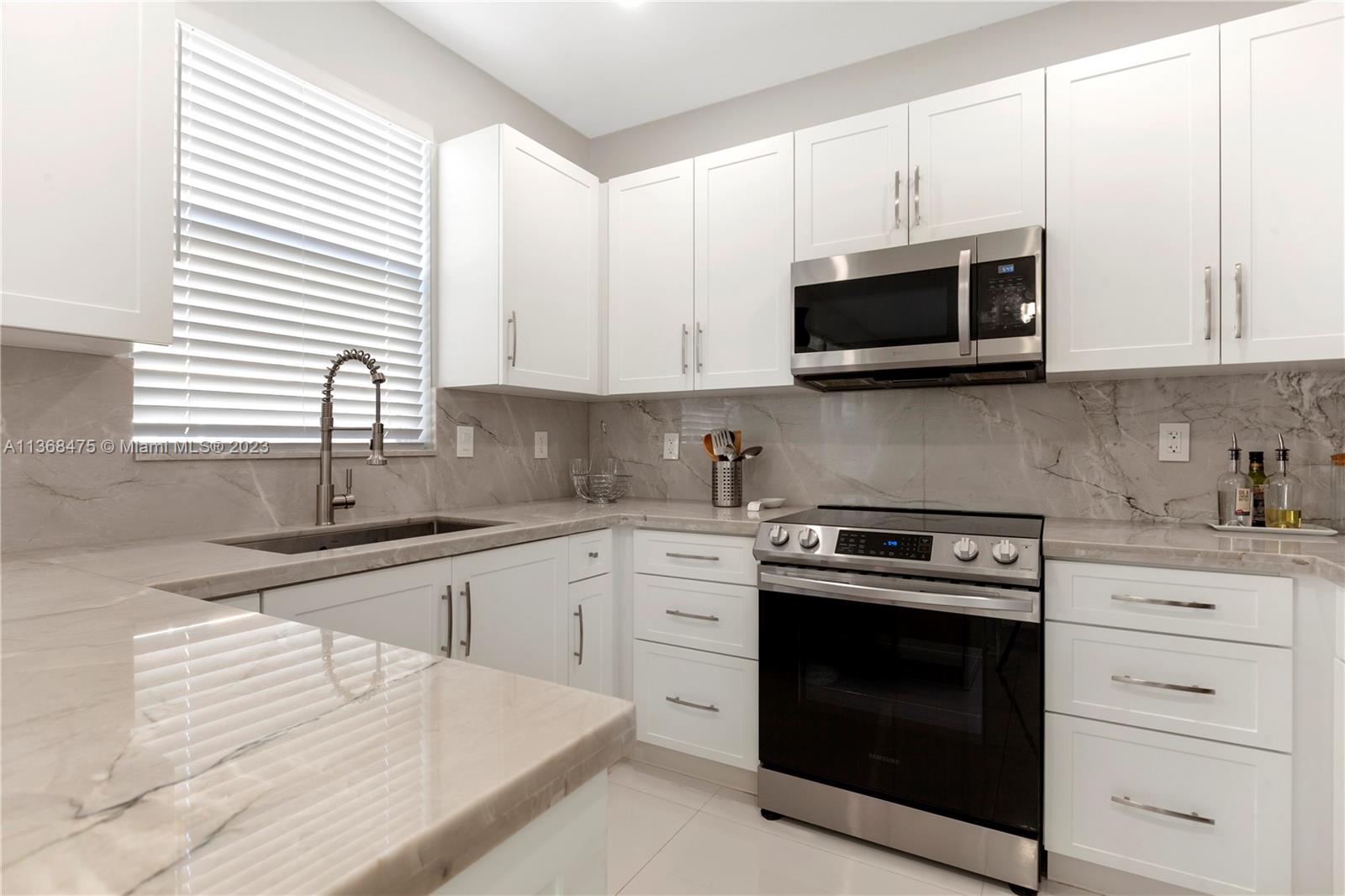 24547 Southwest 109th Avenue Homestead, FL 33032 - Photo 7 of 20 a kitchen with stainless steel appliances granite countertop grey cabinets a stove a sink and a microwave