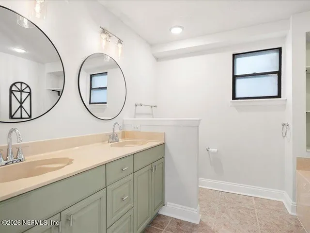 a bathroom with a granite countertop double vanity sink and a mirror