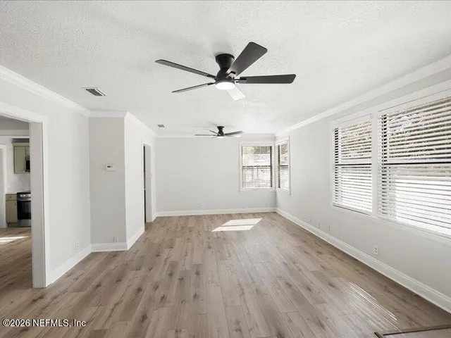 a view of empty room with wooden floor and fan