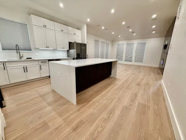 a large white kitchen with wooden floors and white cabinets