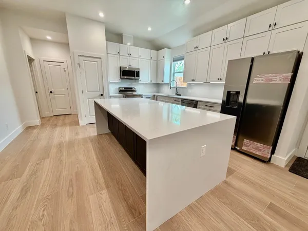 a kitchen with stainless steel appliances granite countertop white cabinets a sink and a oven