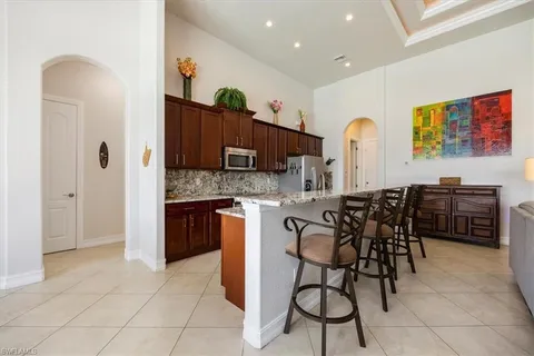 a kitchen with stainless steel appliances a sink a stove a refrigerator cabinets and dining table