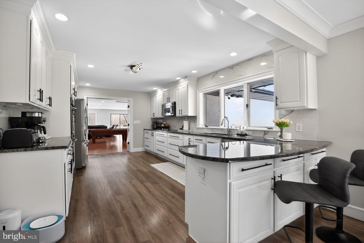 4304 Bridgeboro Road Moorestown, NJ 08057 - Photo 11 of 40 a kitchen with stainless steel appliances kitchen island granite countertop a sink a stove a refrigerator and white cabinets with wooden floor