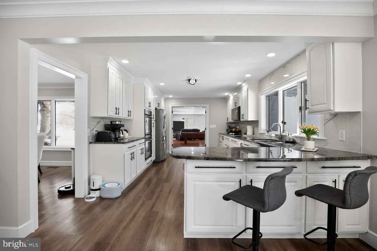 4304 Bridgeboro Road Moorestown, NJ 08057 - Photo 14 of 40 a kitchen with stainless steel appliances kitchen island granite countertop a stove a sink a refrigerator and white cabinets with wooden floor