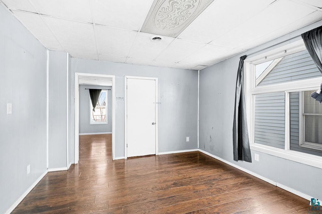 605 Weeks Avenue Superior, WI 54880 - Photo 4 of 21 Empty room with a paneled ceiling and dark wood-style flooring