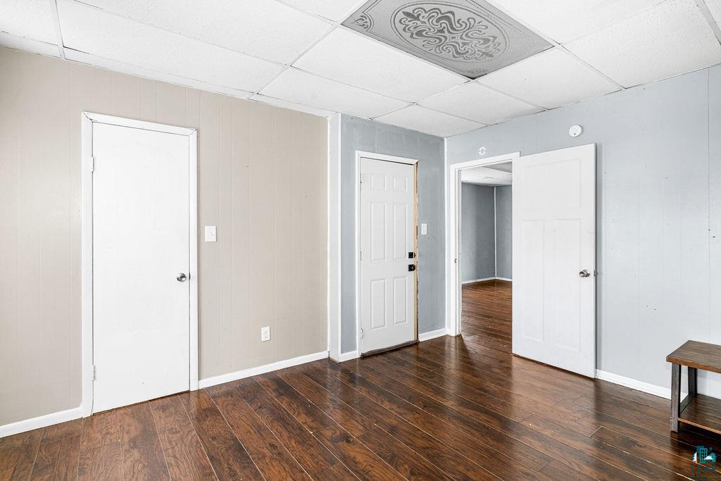 605 Weeks Avenue Superior, WI 54880 - Photo 6 of 21 Unfurnished bedroom with a paneled ceiling, dark wood finished floors, and wooden walls