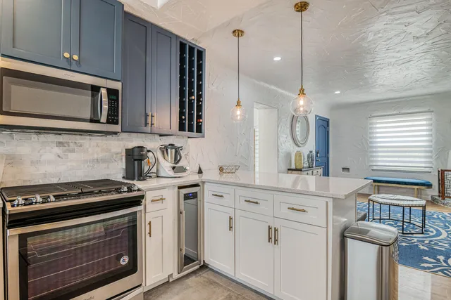 a kitchen with stainless steel appliances a stove a sink cabinets and a wooden floor