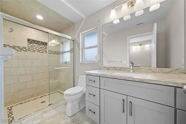 a bathroom with a granite countertop sink a toilet and shower