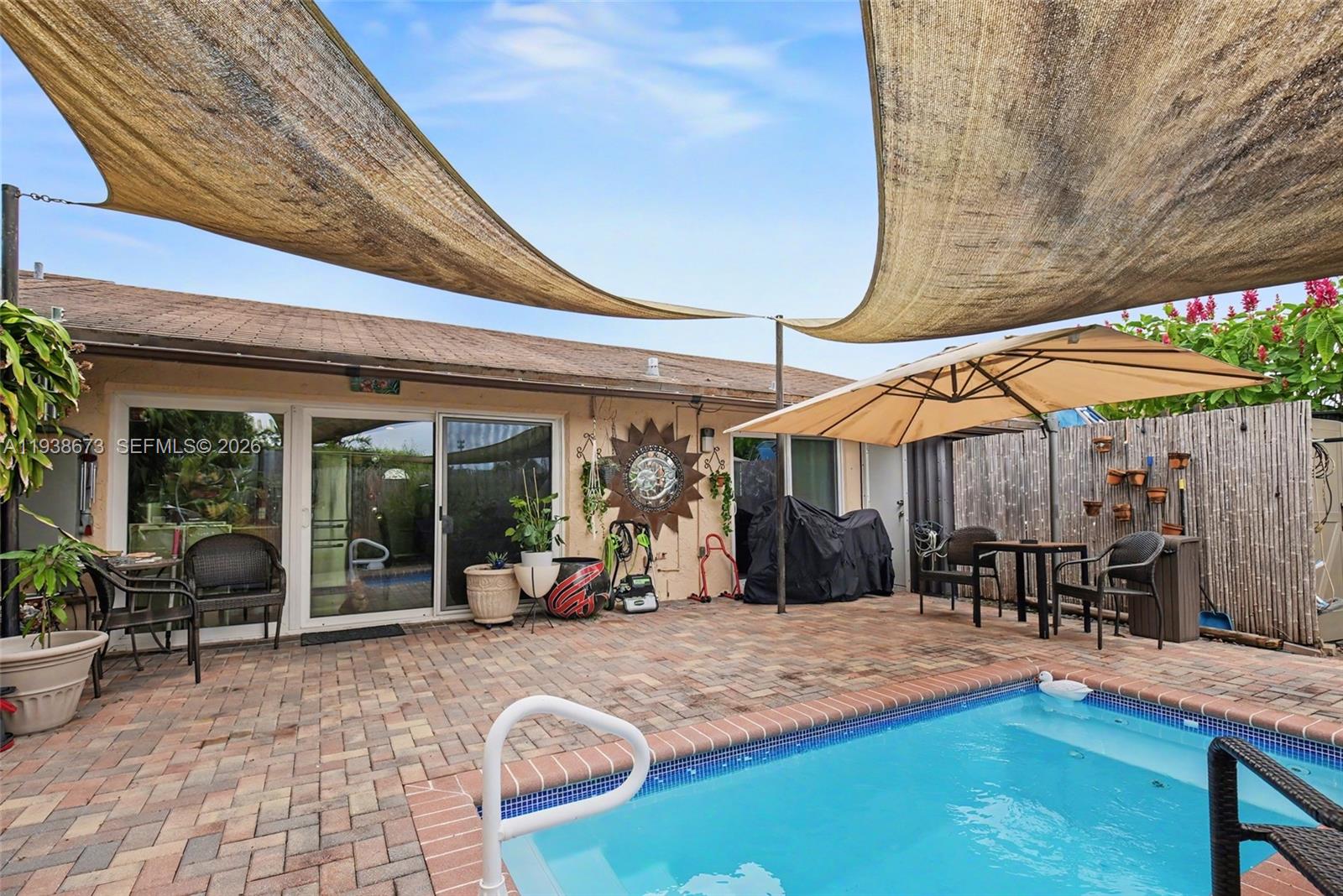 13574 Southwest 49th Lane Miami, FL 33175 - Photo 26 of 36 a view of a patio with table and chairs under an umbrella with a barbeque grill and couches