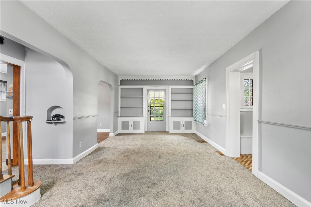302 Poplar Avenue Northwest Canton, OH 44708 - Photo 6 of 34 Unfurnished living room featuring arched walkways, carpet flooring, and built in shelves