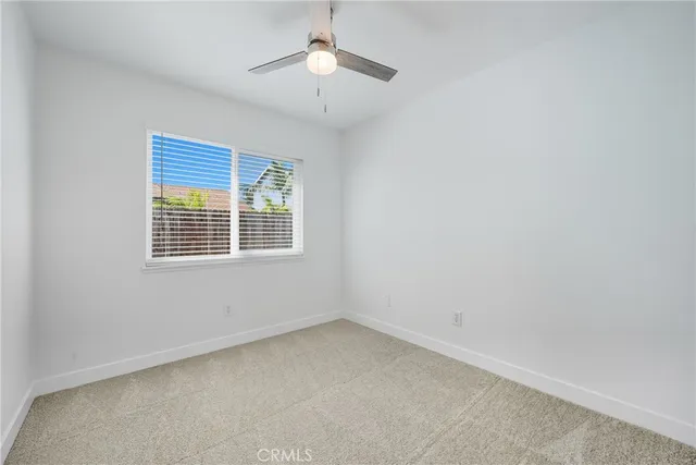 an empty room with a window and a ceiling fan