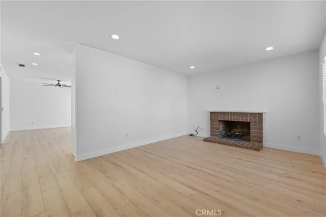 an empty room with wooden floor fireplace and windows