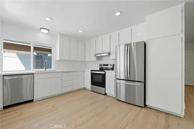 a kitchen with a refrigerator and white cabinets