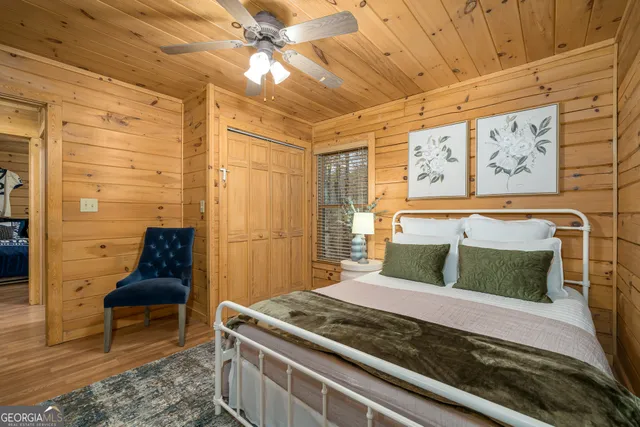 a spacious bedroom with a bed and a flat tv screen on dresser