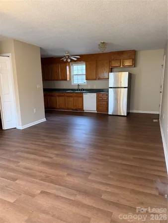 a view of a kitchen with wooden floor and a hallway