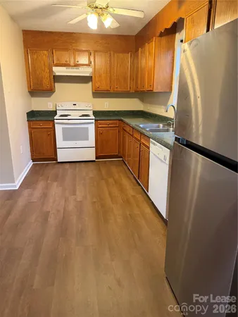 a kitchen with granite countertop a refrigerator a sink and white cabinets