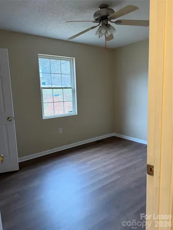 an empty room with wooden floor fan and windows