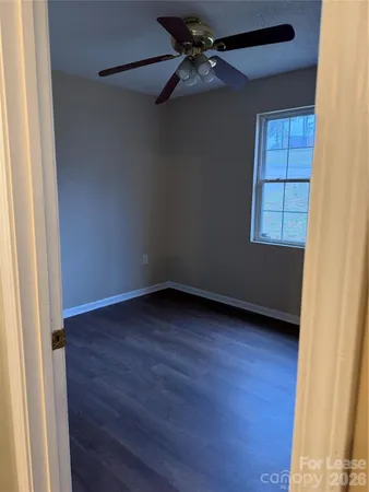 an empty room with wooden floor closet and windows