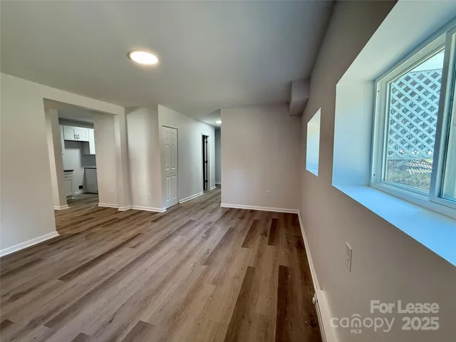 a view of an empty room with wooden floor and a window