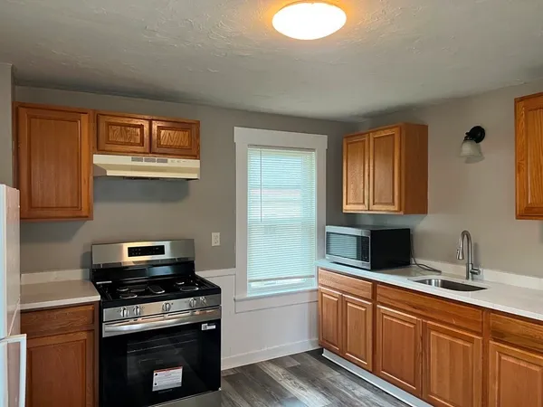 a kitchen with granite countertop a stove sink and cabinets