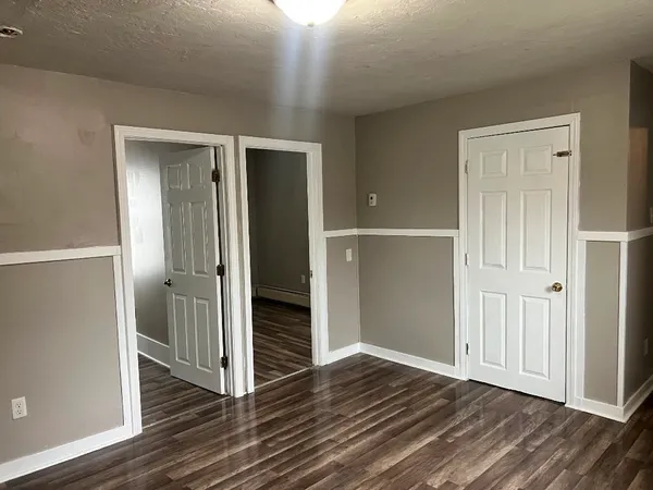 an empty room with wooden floor & closet area