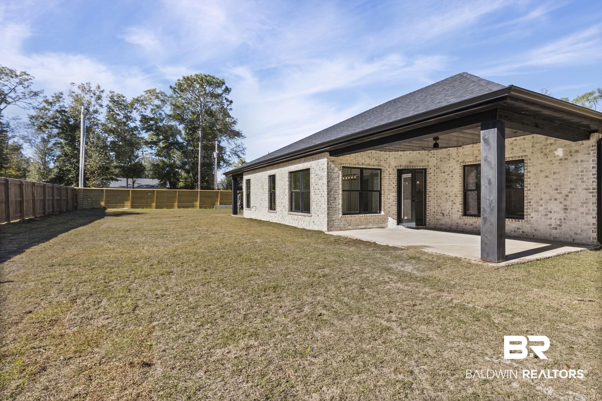 10180 Pineview Drive Foley, AL 36535 - Photo 33 of 47 Back of property with brick siding, a patio area, and a fenced backyard