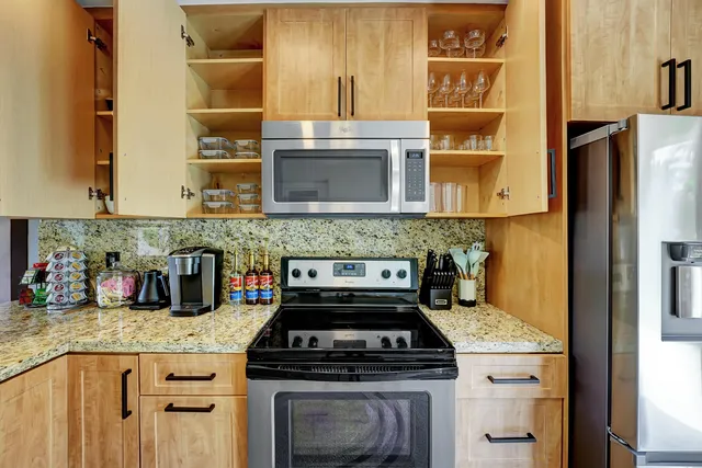 a kitchen with granite countertop a stove a sink and a microwave